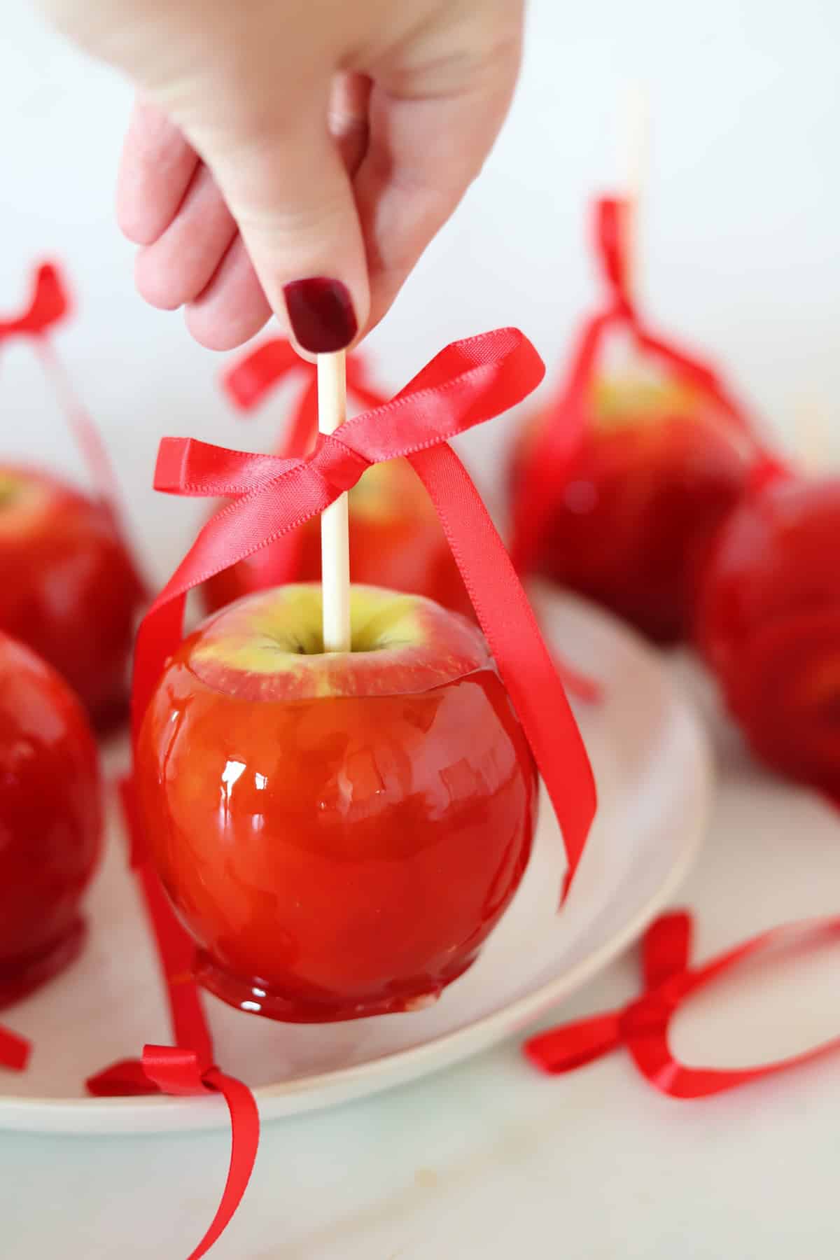 A candy apple is being picked up by a hand.