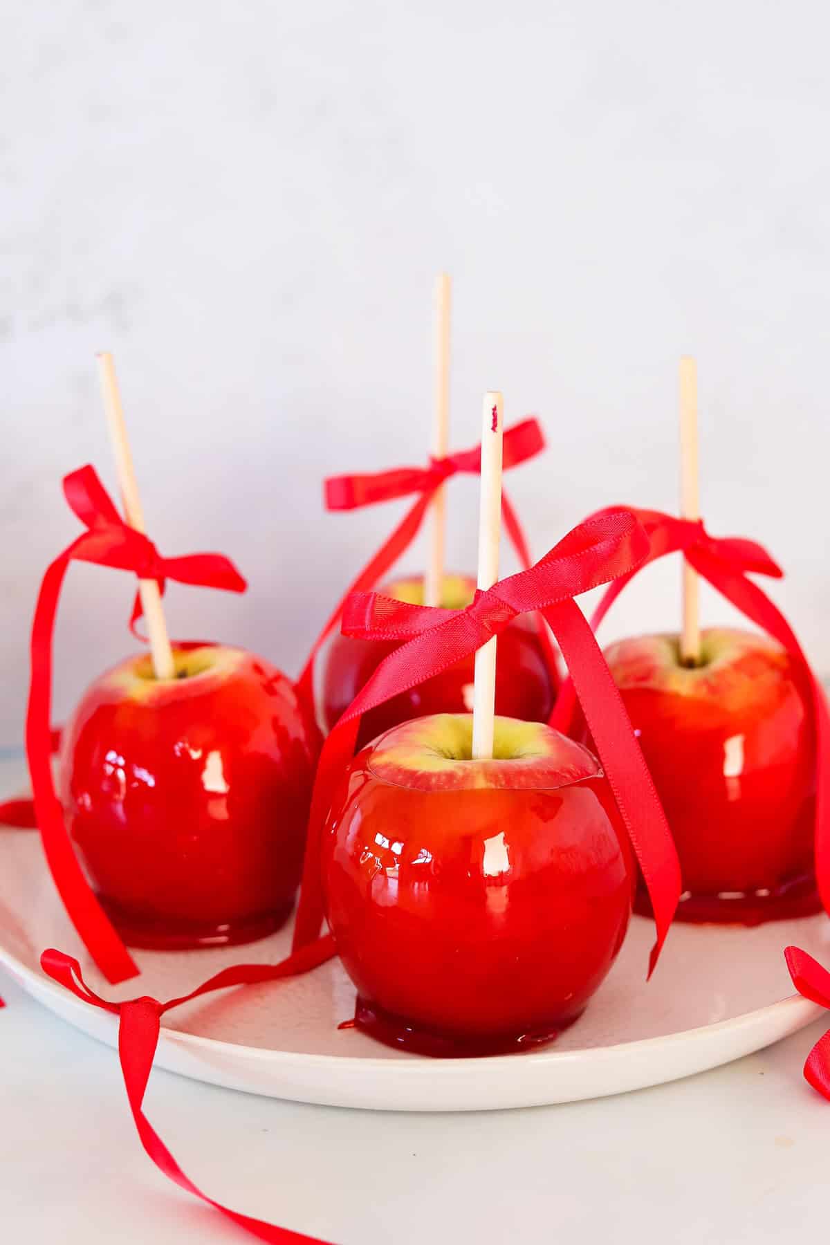 Close up of candy apples on a white plate.